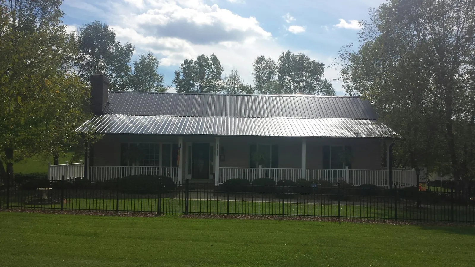 Gray metal roof on a brick ranch with a full width front porch — Gutter Guard Installation work by our crew in Alberta